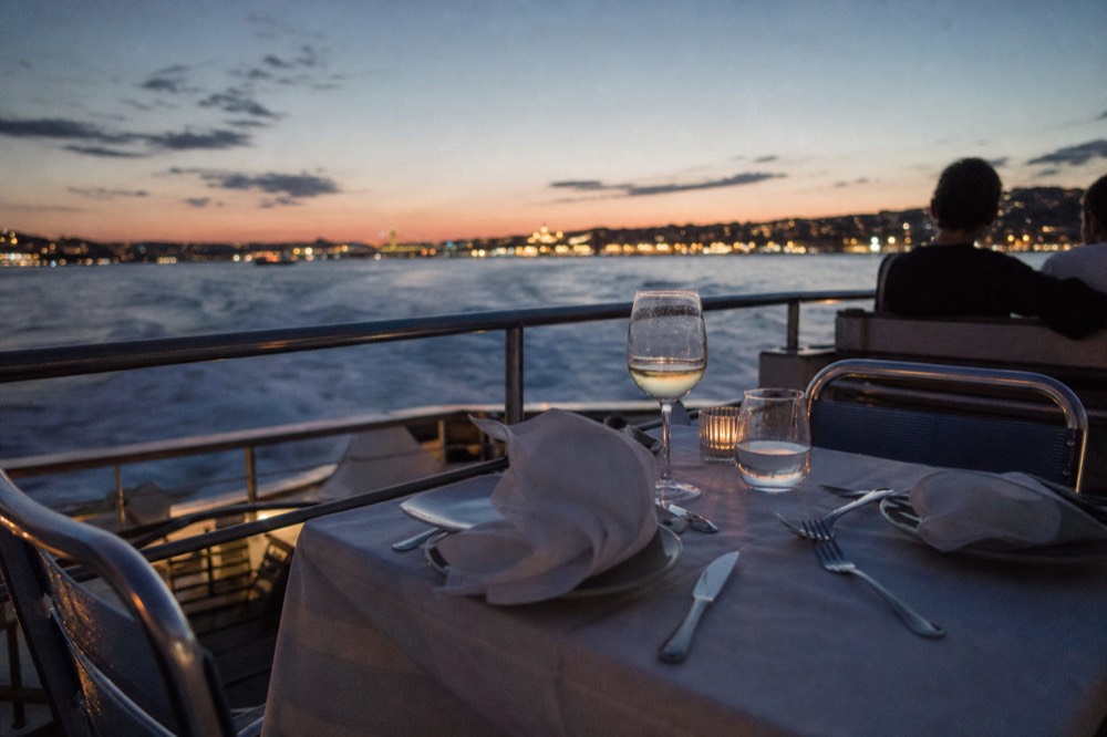 A couple's table set for dinner on a boat deck at twilight, no text, no logos, no people