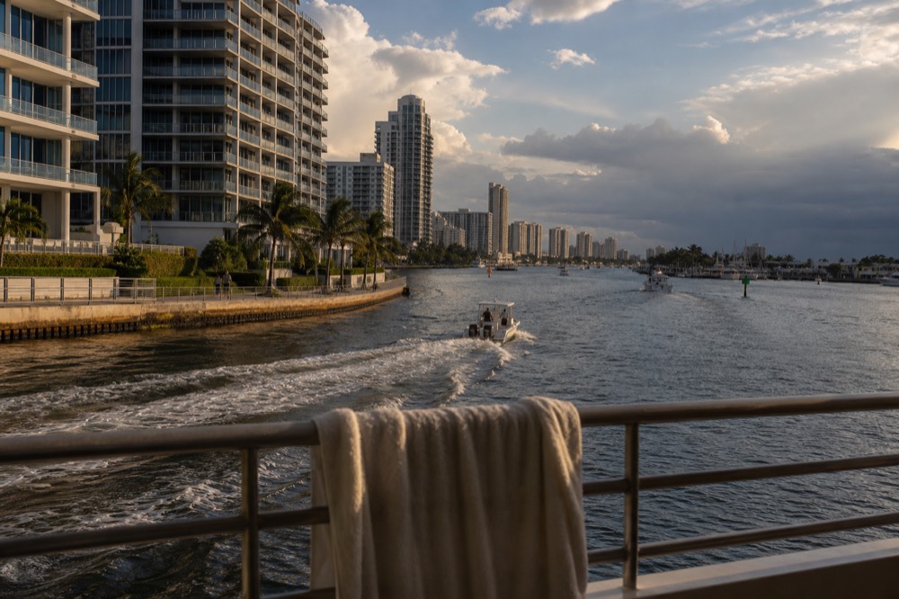 Golden hour light on the Intracoastal Waterway with a water taxi wake trailing toward waterfront high-rises, no text, no logos, no people