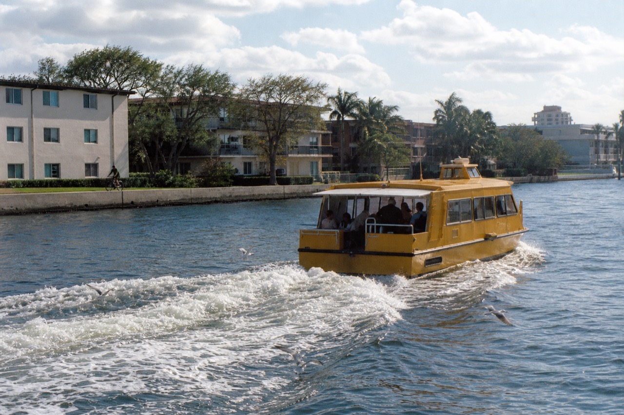 A yellow water taxi cruising the Intracoastal Waterway past Fort Lauderdale waterfront buildings, no text, no logos, no people
