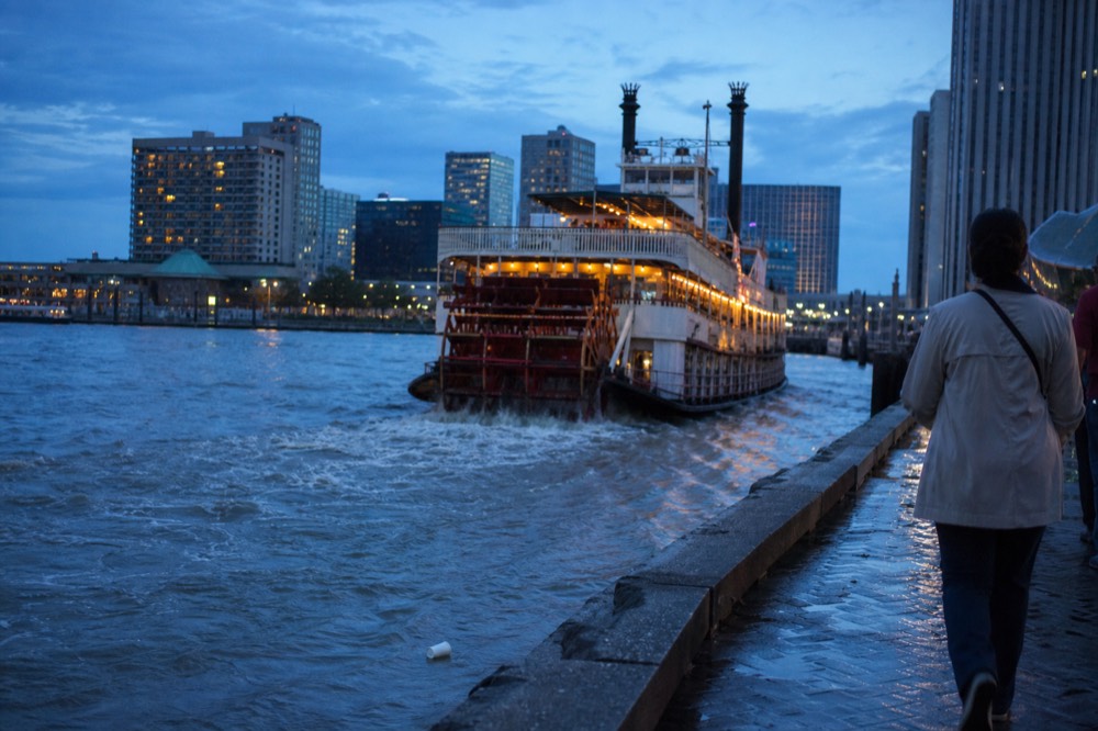 Paddlewheel riverboat lit up at dusk on the New River, no text, no logos, no people