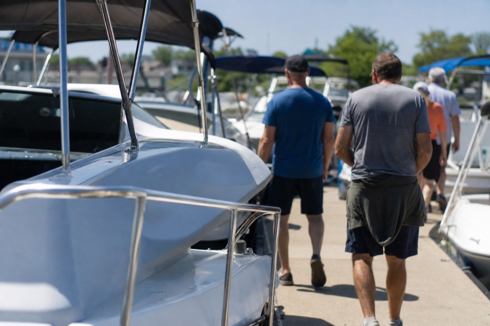 Visitors in casual summer clothing browsing boats on a sunny dock, no text, no logos, no people