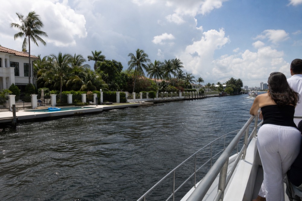 A small cruise boat passing a row of waterfront mansions along the Intracoastal Waterway, no text, no logos, no people