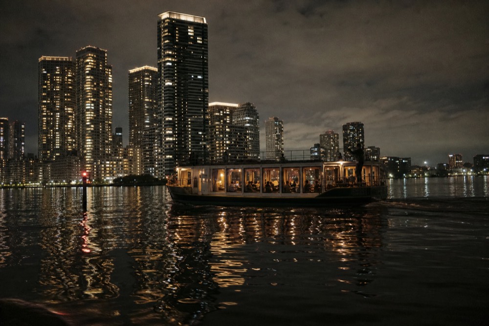 An evening dinner cruise boat underway on calm city waterways, no text, no logos, no people
