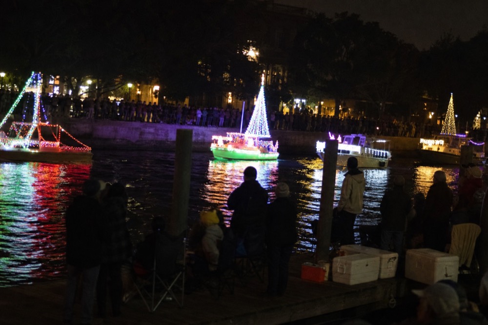 Decorated boats with bright lights gathered on a river for an evening parade, no text, no logos, no people