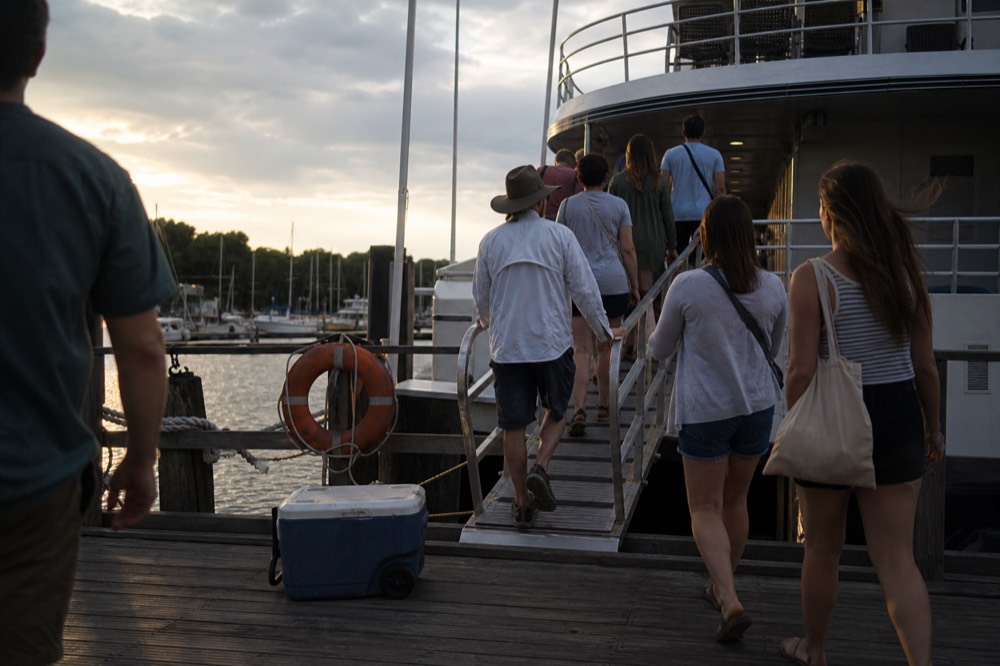 Passengers boarding a riverboat at a marina dock in the early evening, no text, no logos, no people