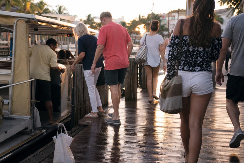 Passengers boarding a water taxi at the Las Olas stop with shops and palm trees in the background, no text, no logos, no people