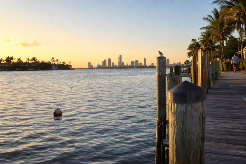 Golden hour over the Intracoastal Waterway with docks and distant skyline, no text, no logos, no people.