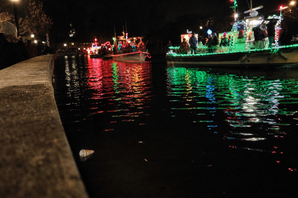 Illuminated parade boats reflected in the New River at night, no text, no logos, no people.
