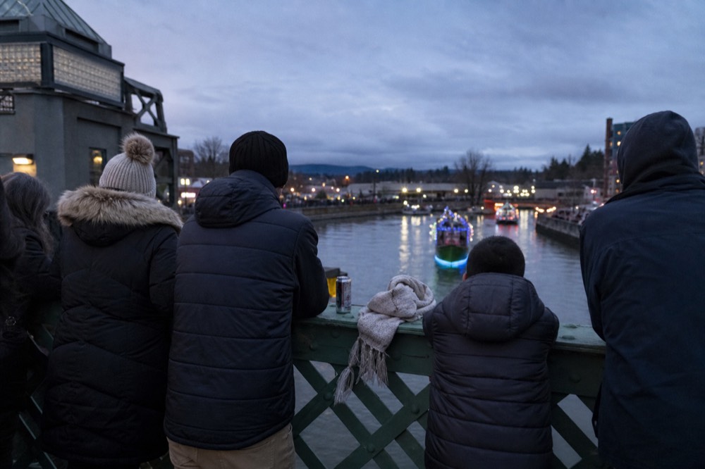 Crowds gathered on a bridge above a waterway waiting for decorated boats, no text, no logos, no people.