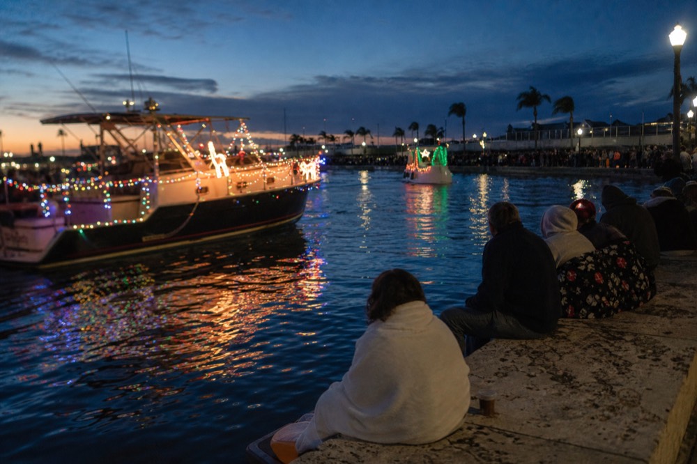 Decorated boats passing a dockside crowd under evening sky, no text, no logos, no people.